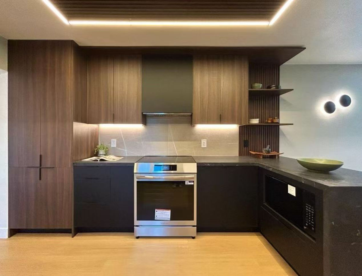 Modern kitchen cabinetry setup with dark wood upper cabinets, dark lower cabinets, a stainless steel built-in oven, a black microwave, open shelving, and warm under-cabinet lighting.